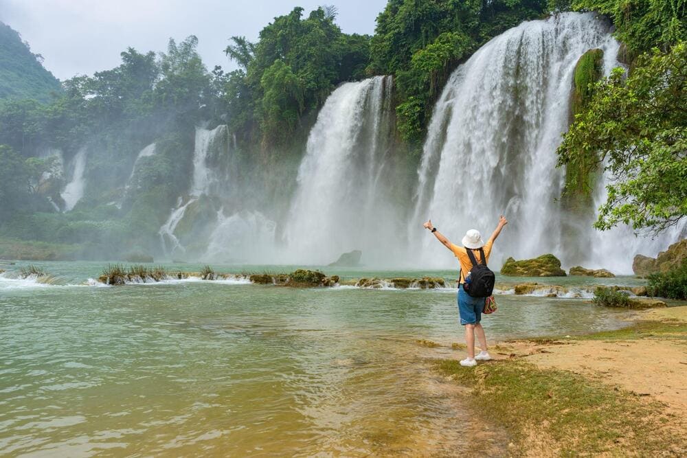 The closer you get, the more you can admire the intricate layers of water pouring down moss-covered rocks, surrounded by lush vegetation (Source: Freepik)